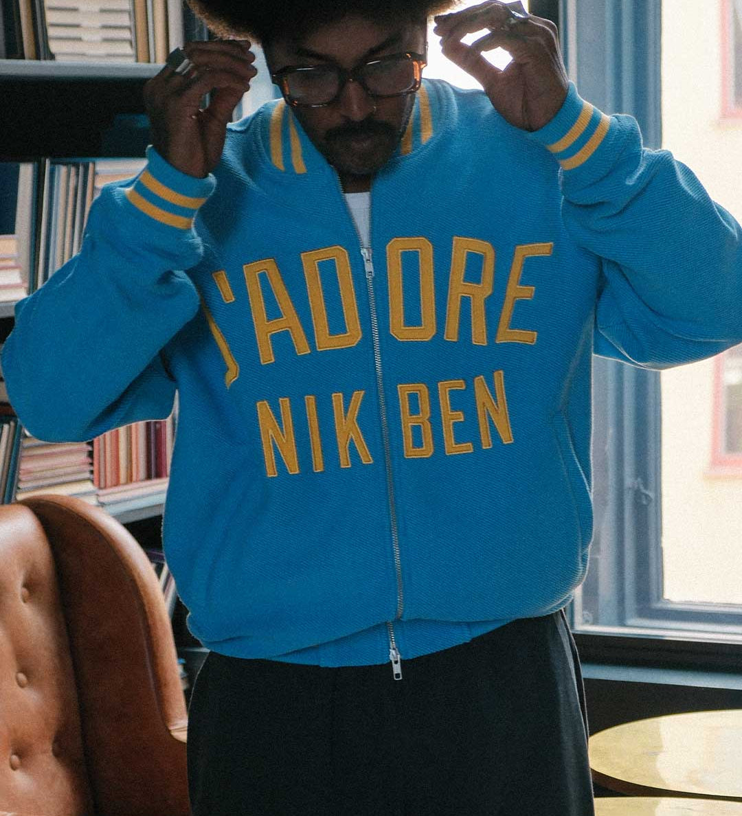 Model wearing Blue bomber jacket with yellow text on front