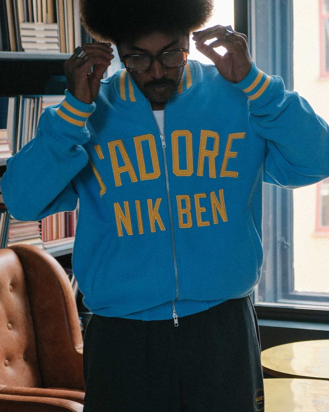 Model wearing Blue bomber jacket with yellow text on front