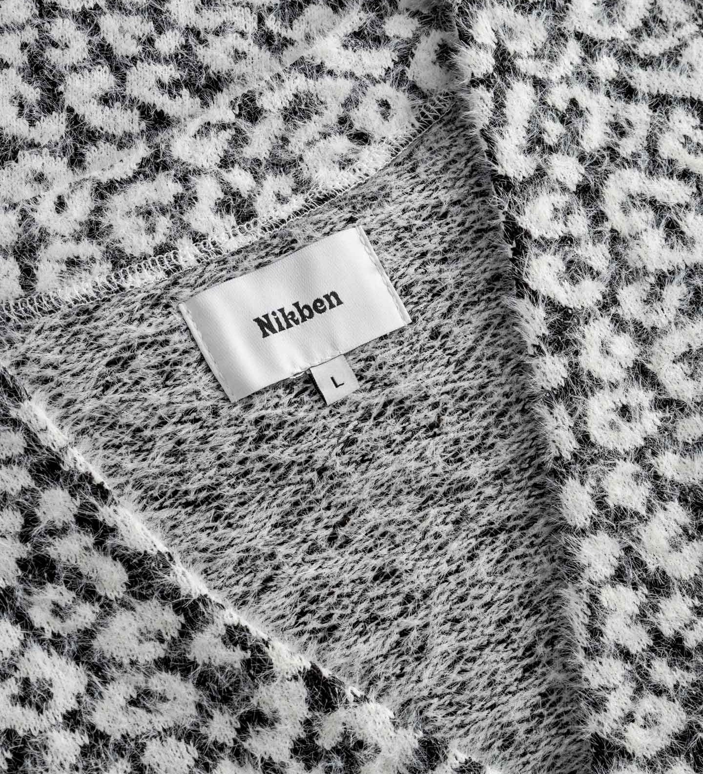  Label displaying the brand 'Nikben'. on a black white cardigan