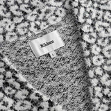  Label displaying the brand 'Nikben'. on a black white cardigan