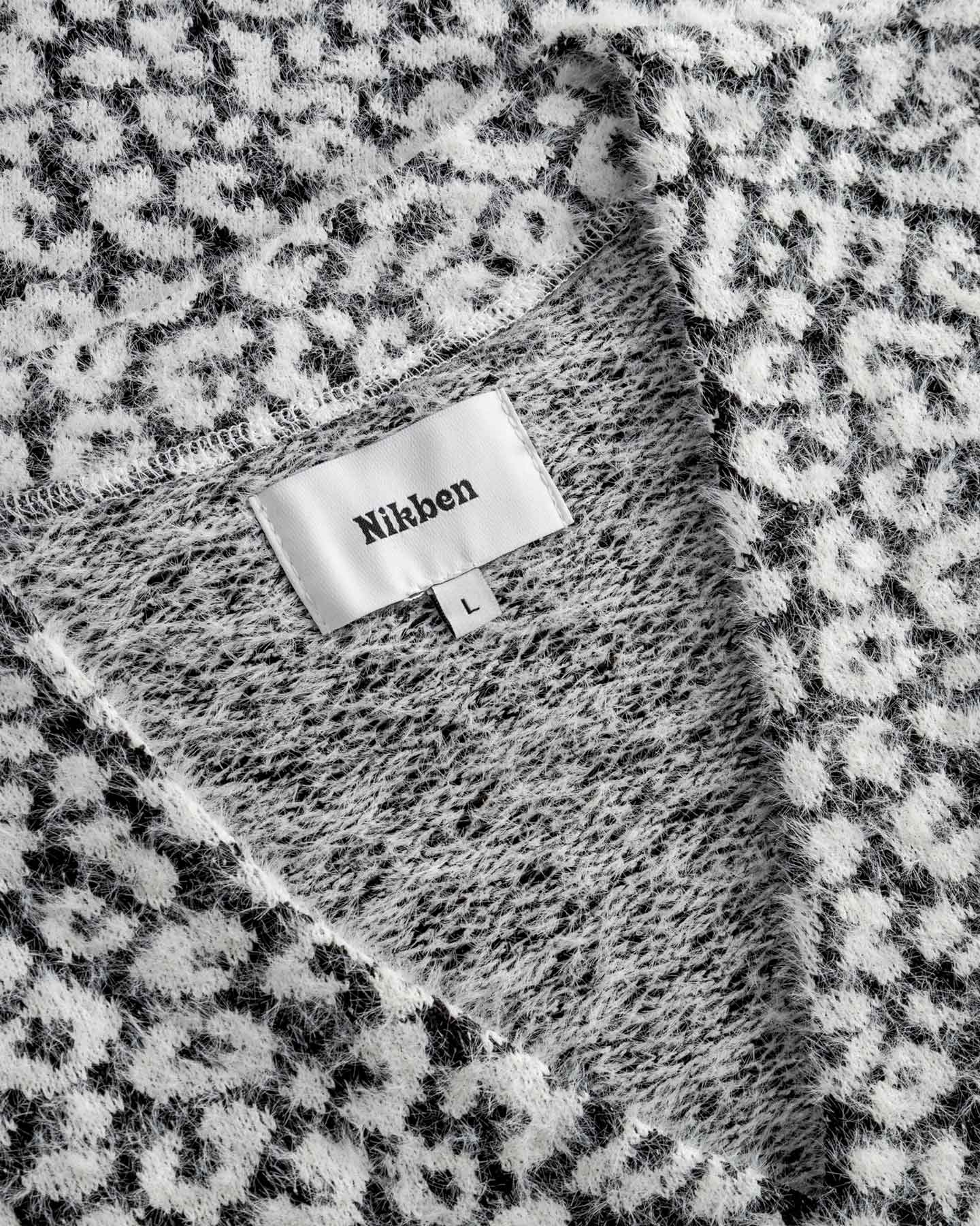  Label displaying the brand 'Nikben'. on a black white cardigan