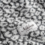 Nikben label on a textured black and white fabric cardigan