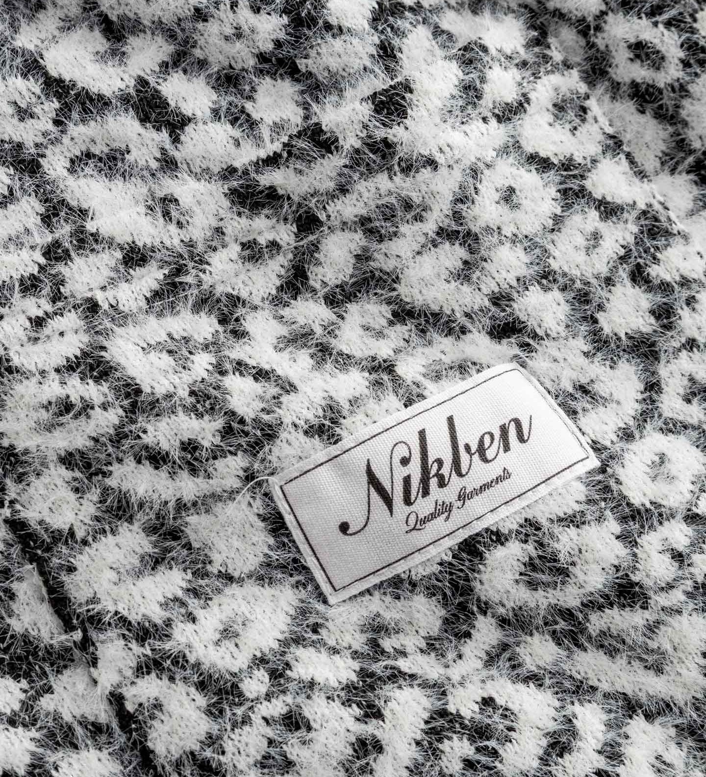Nikben label on a textured black and white fabric cardigan