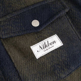Close up on dark blue and green flannel overshirt front breast pocket with Nikben brand logo