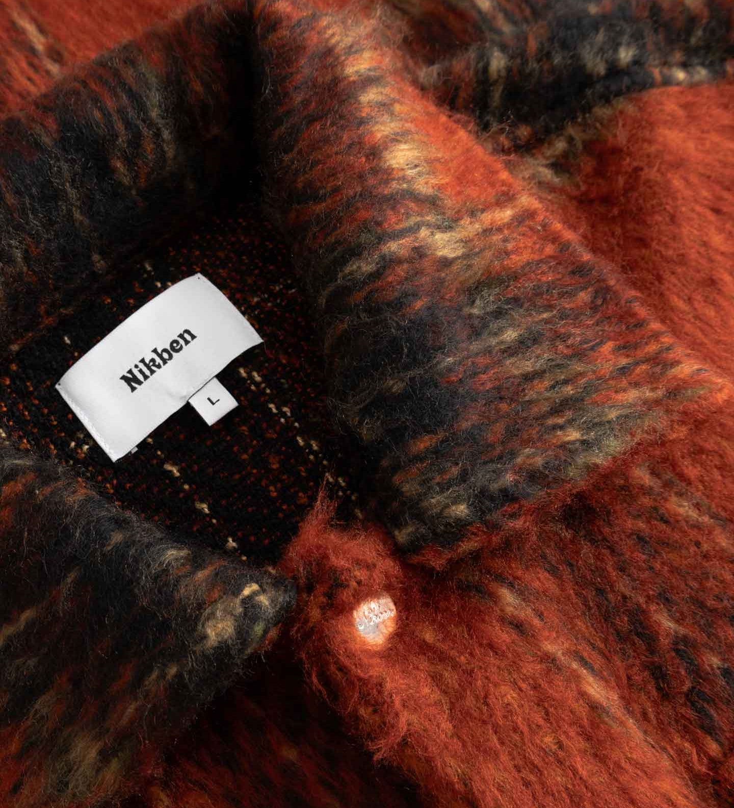 Close-up detail of a red and black checkered fabric with  Nikben label.