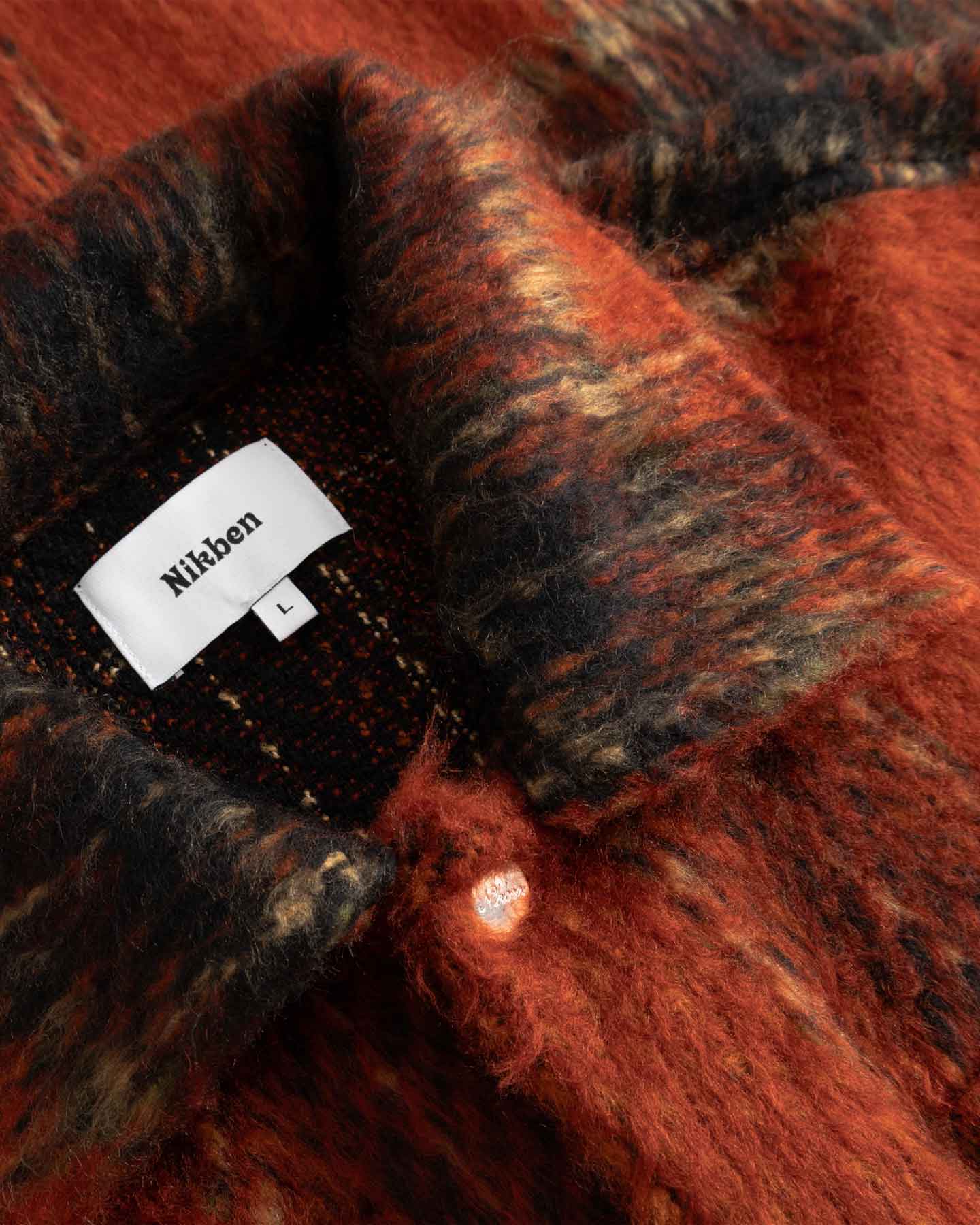 Close-up detail of a red and black checkered fabric with  Nikben label.