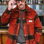 Model wearing a red plaid overshirt open with front breast button down pockets