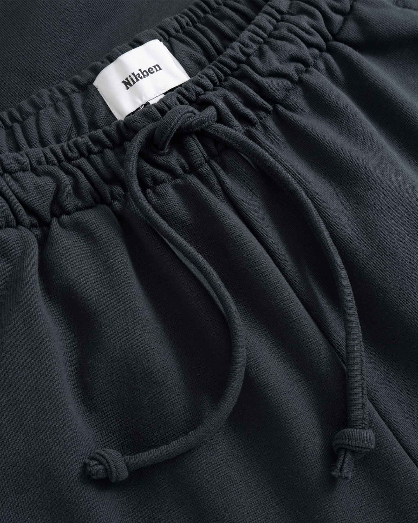 Black pants with a drawstring and visible brand label 