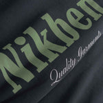 Close up of Black fabric with green and white text 'Nikben' and 'Quality Garments'
