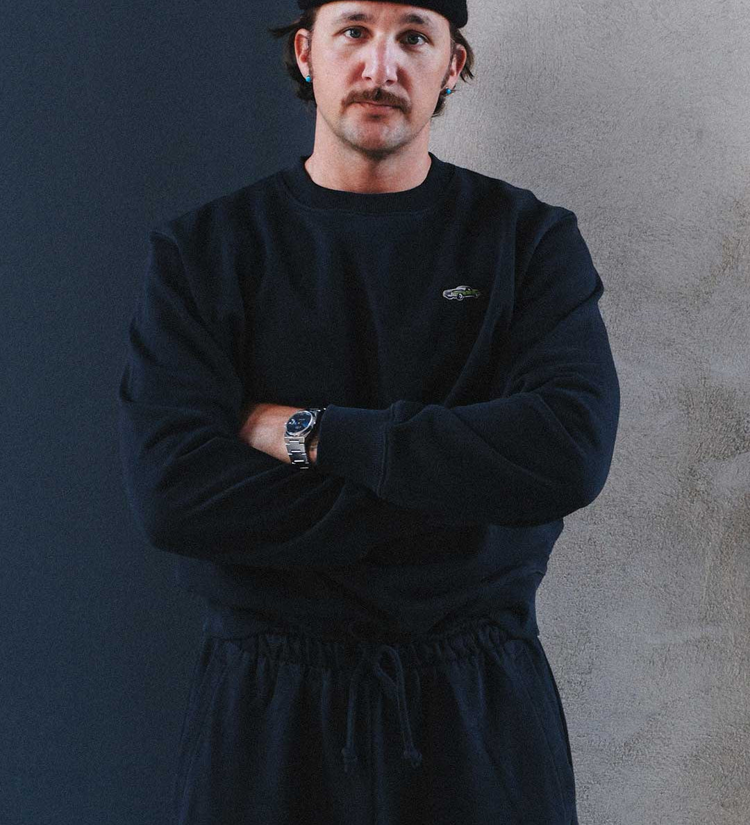 Model wearing a black sweatshirt and pants with a logo on chest.
