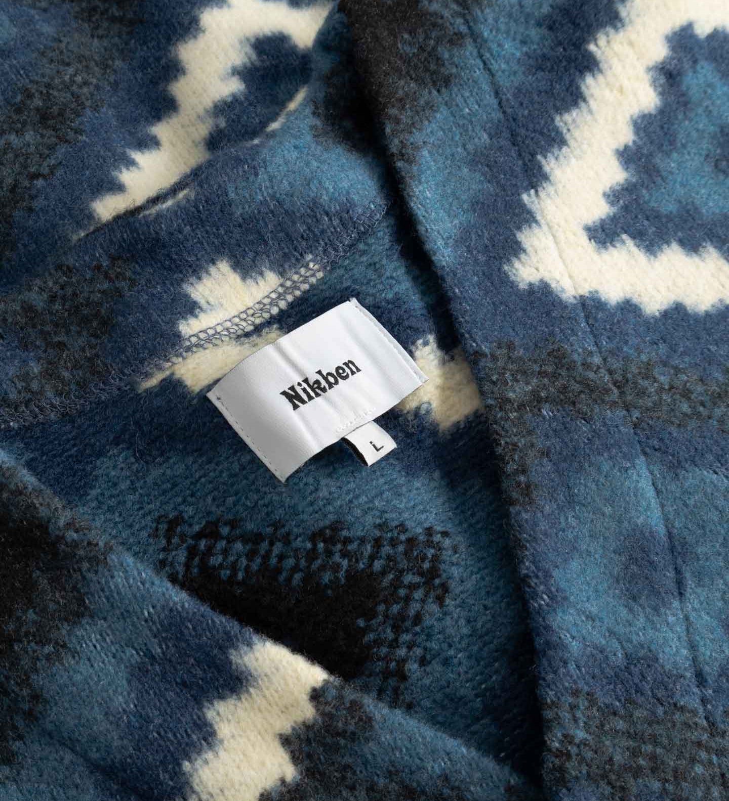 Close up of blue and white diamond Ikat patterned fabric with visible brand label