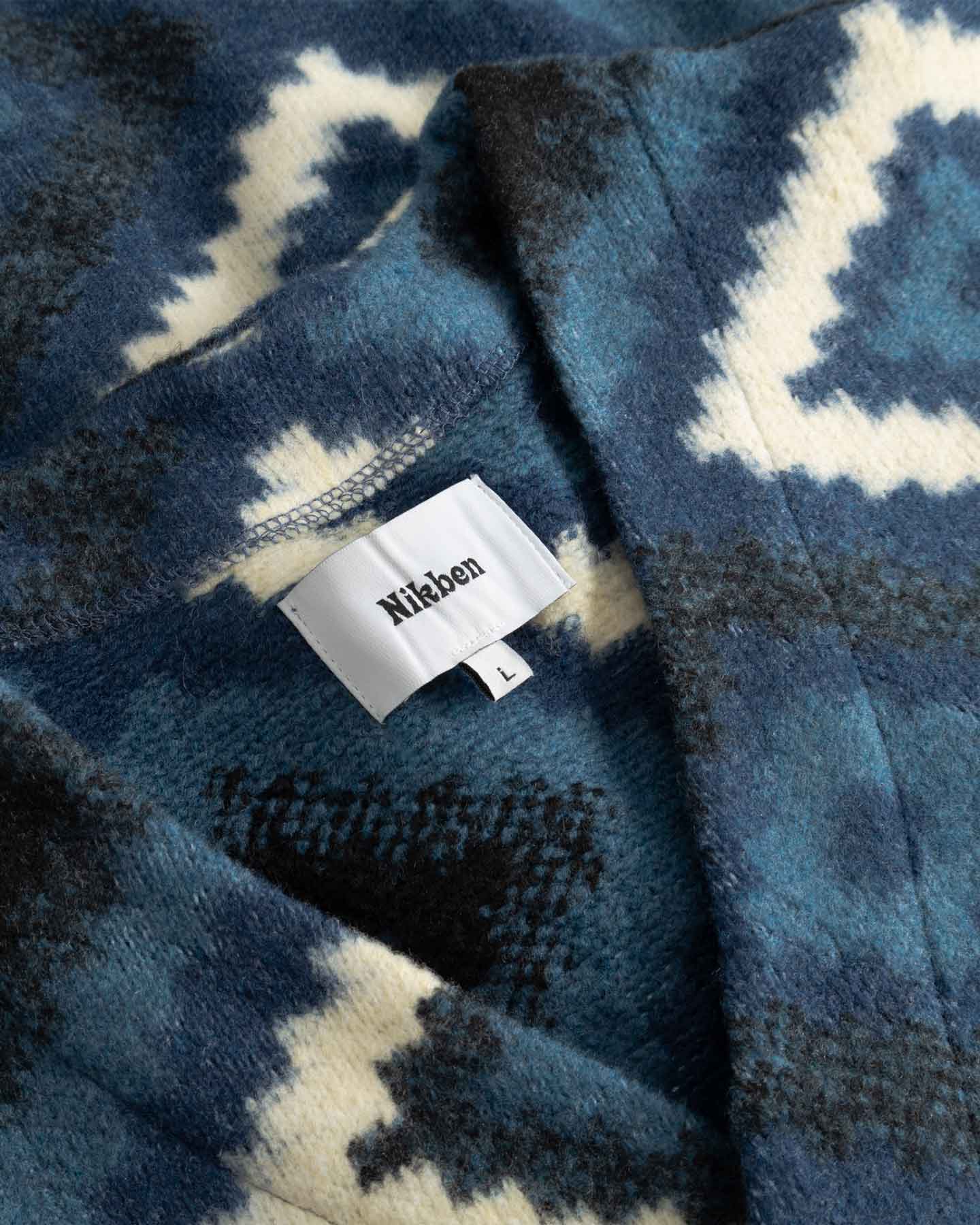 Close up of blue and white diamond Ikat patterned fabric with visible brand label