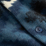 Close-up of textured fabric with buttons on a blue and black diamond Ikat patterned cardigan