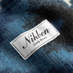 Close up of Nikken label on a blue and white Diamond Ikat Patterned  Cardigan