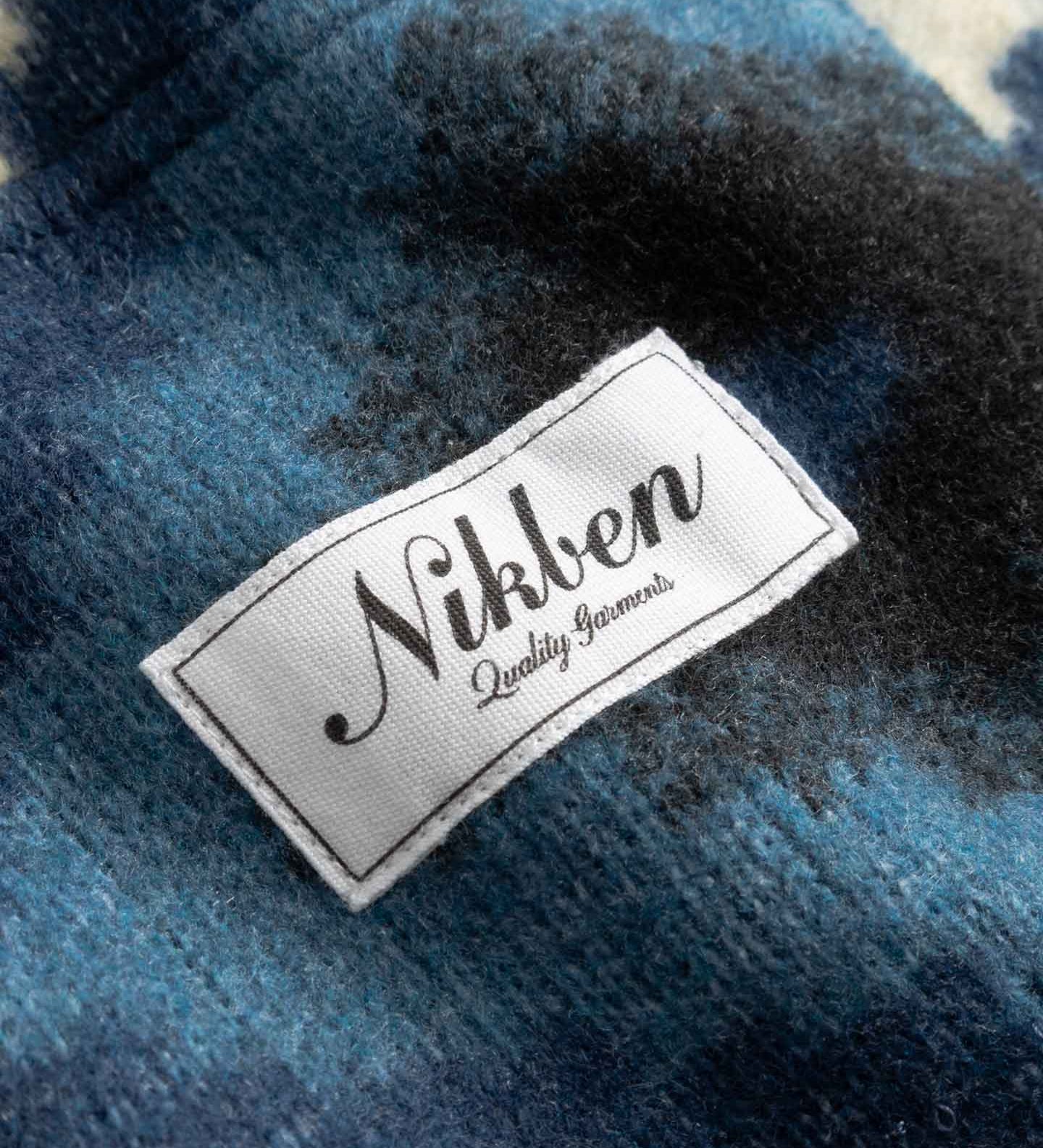 Close up of Nikken label on a blue and white Diamond Ikat Patterned  Cardigan