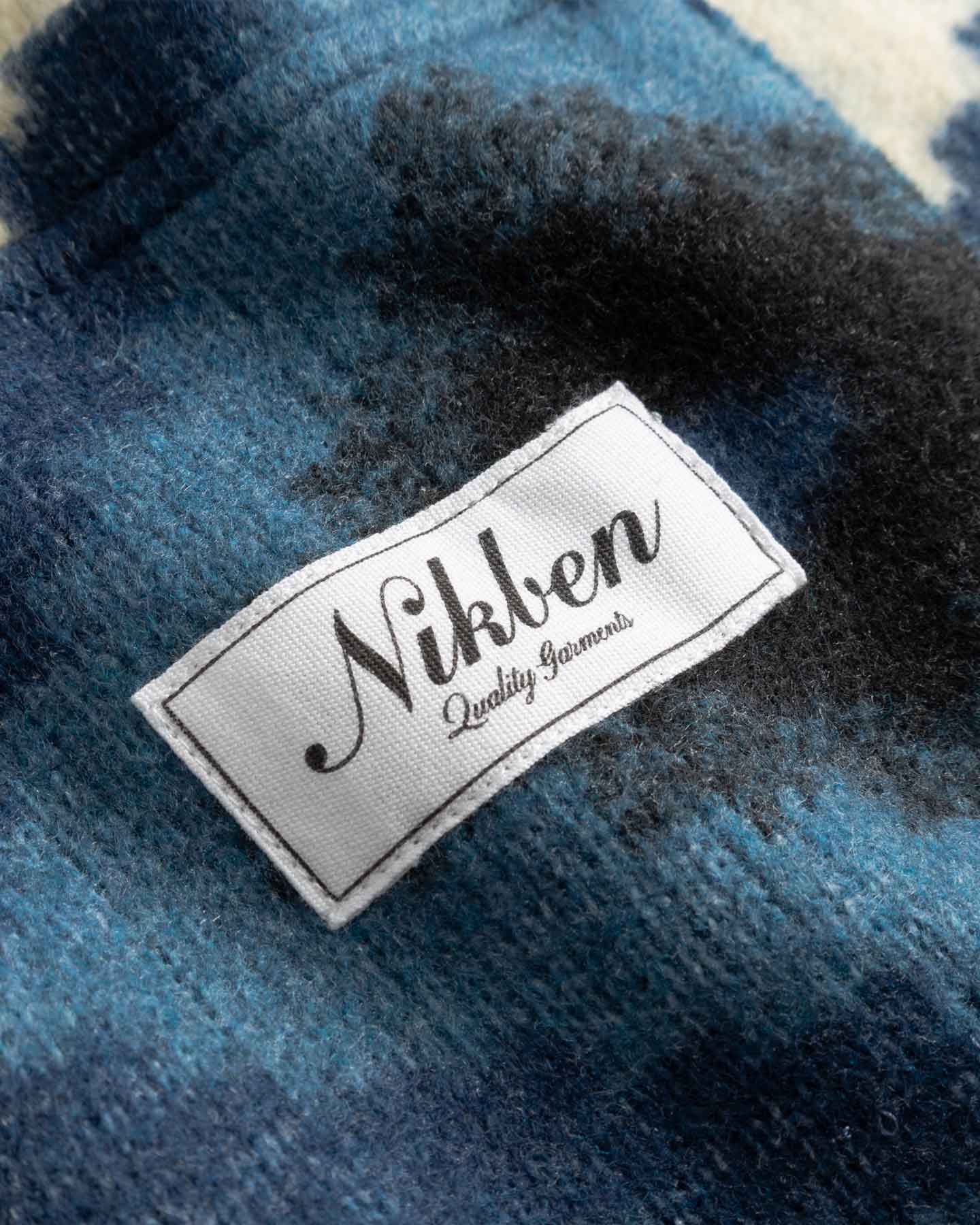 Close up of Nikken label on a blue and white Diamond Ikat Patterned  Cardigan