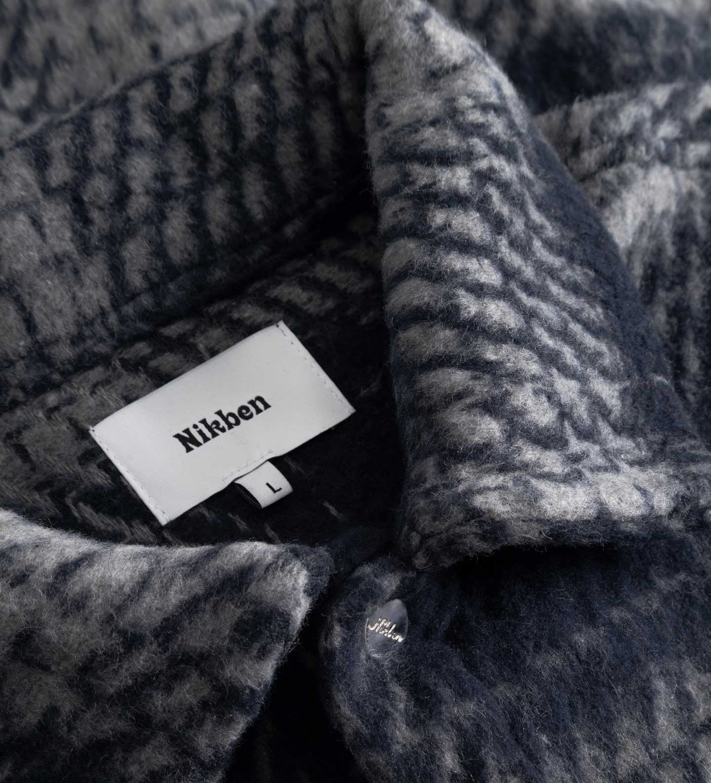 Close up of navy grey checkered pattern on overshirt Nikben label