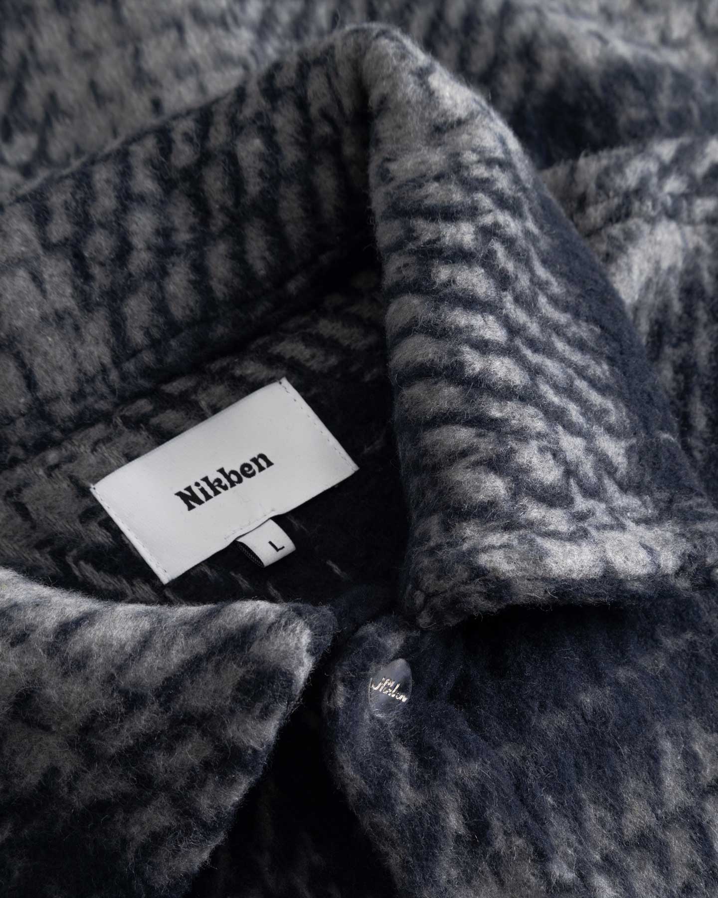 Close up of navy grey checkered pattern on overshirt Nikben label