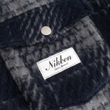 Close up of front chest pocket and logo on navy checkered shirt 
