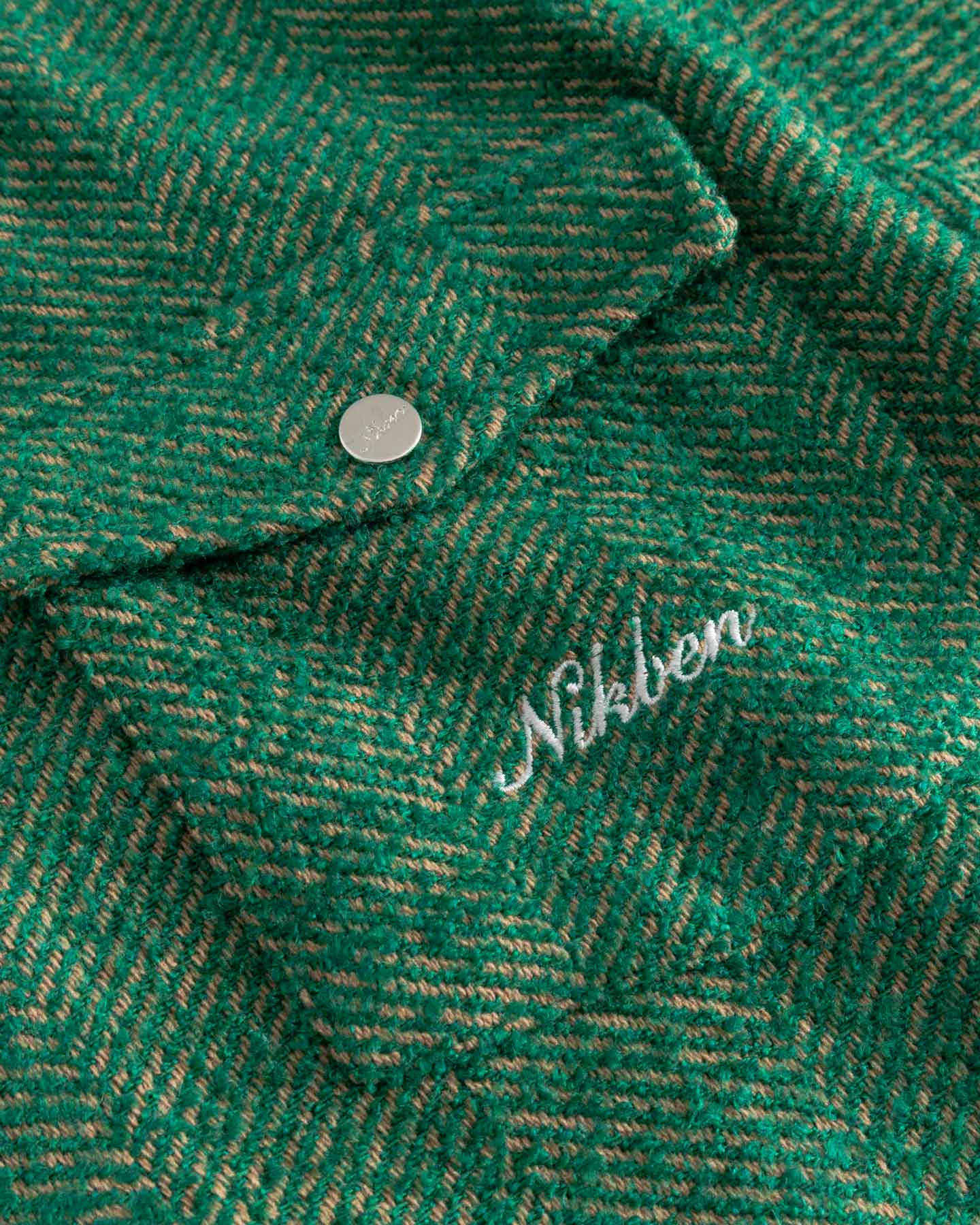 Close-up of a green textured fabric with 'Nikben' branding in white.