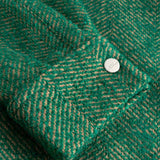 Close-up of a green textured fabric on the cuff with a button down button.