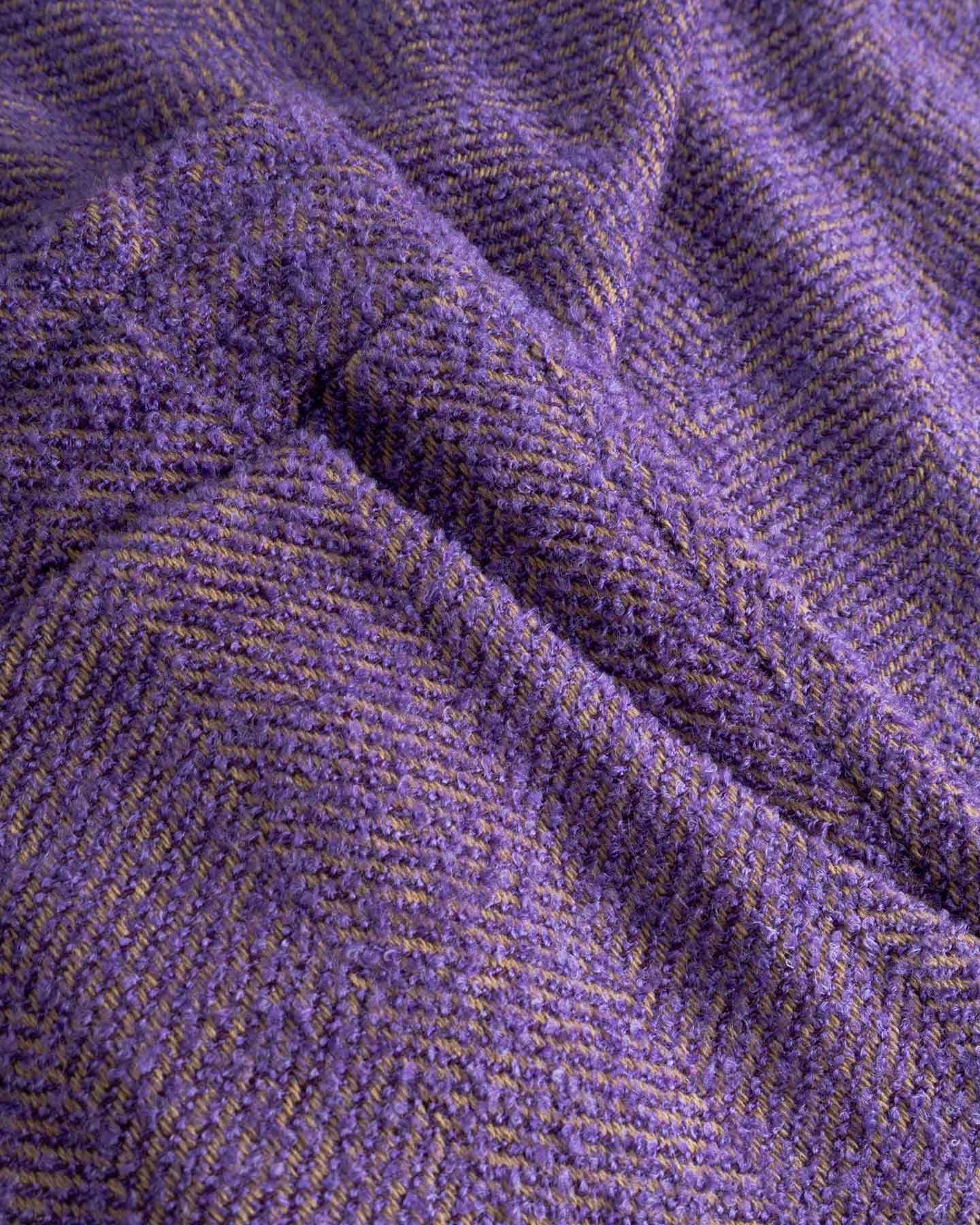 Close-up of textured purple fabric with a herringbone pattern