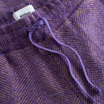 Close-up of a purple textured fabric with a drawstring and visible brand label.