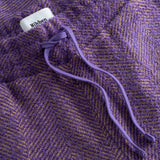 Close-up of a purple textured fabric with a drawstring and visible brand label.