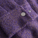 Close-up of  purple textured fabric cuff with a button down button