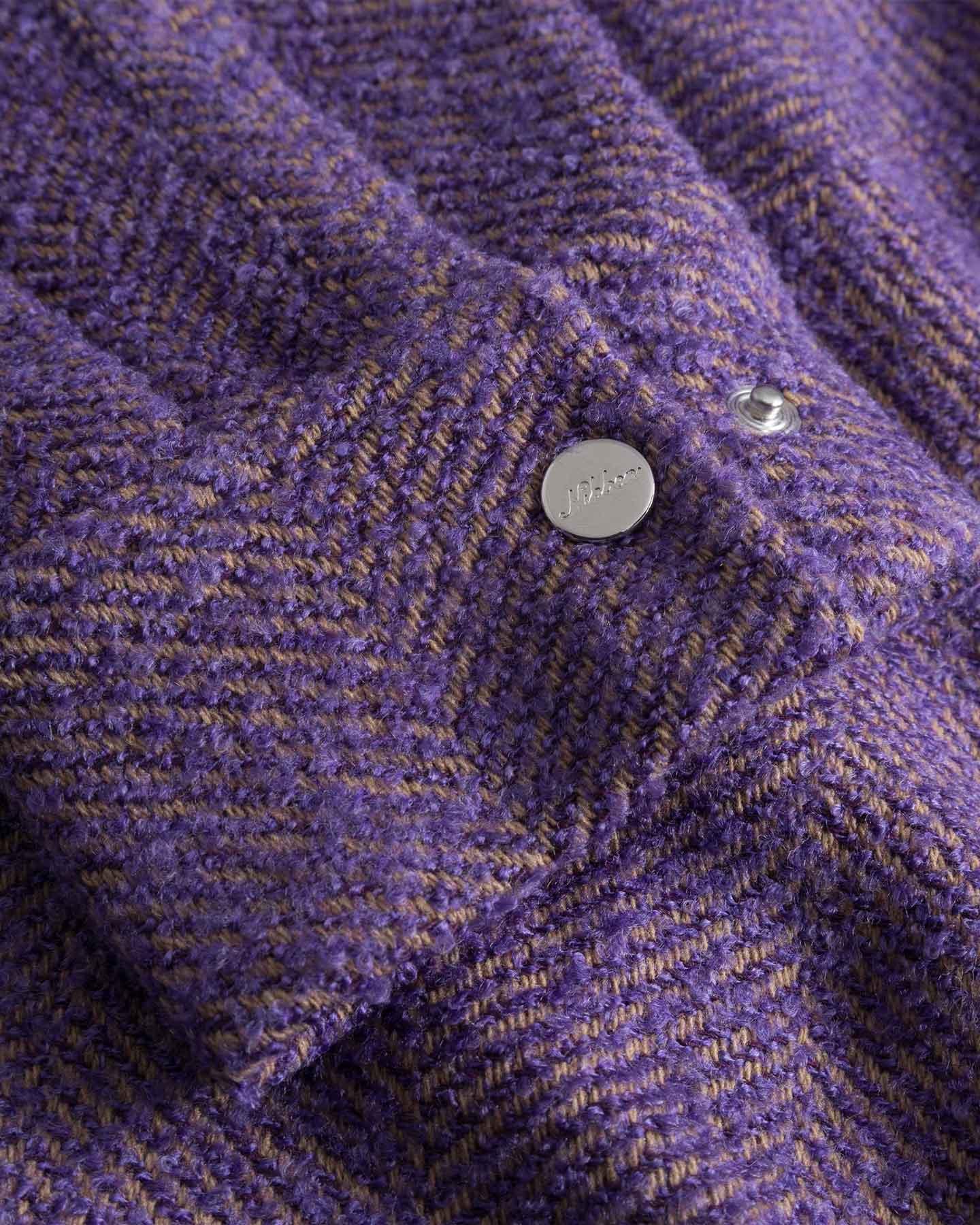 Close-up of  purple textured fabric cuff with a button down button