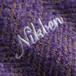 Close-up of a textured purple fabric with 'Nikben' embroidered in white.
