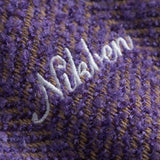 Close-up of a textured purple fabric with 'Nikben' embroidered in white.