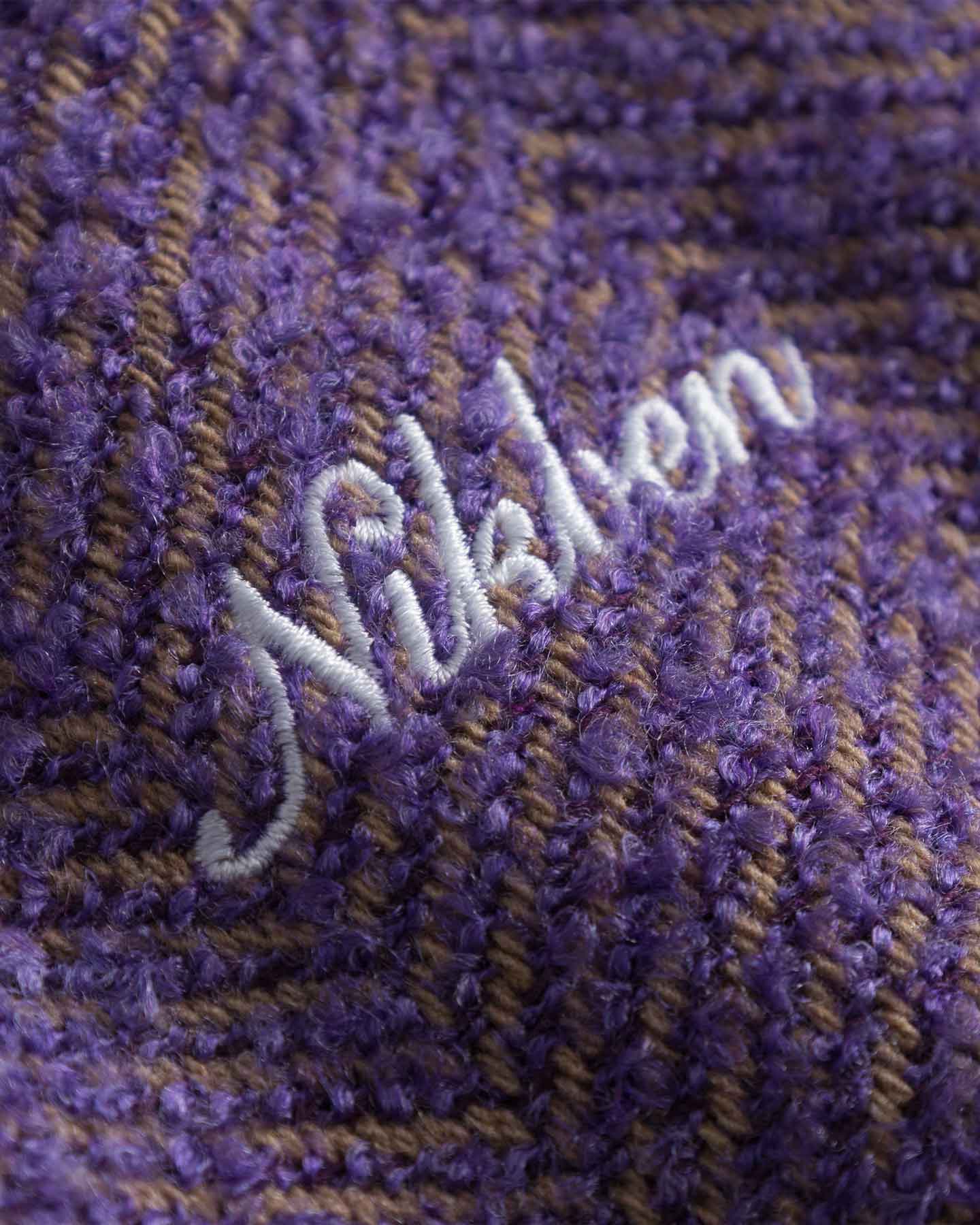 Close-up of a textured purple fabric with 'Nikben' embroidered in white.
