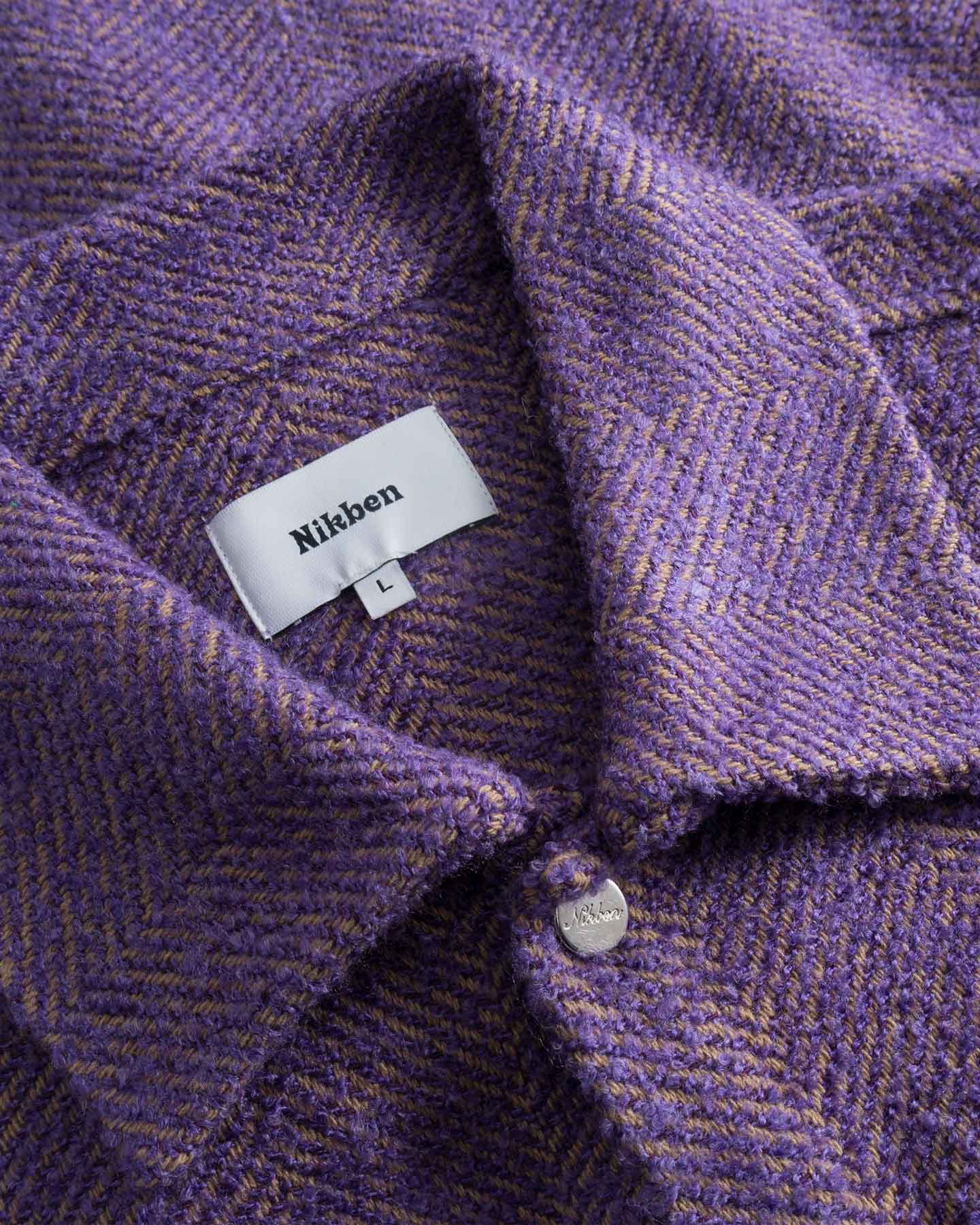 Close-up of a purple textured fabric with a Nikben label.