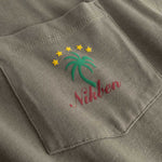 Closeup view of green palm print and red NIKBEN logo on front pocket of green T-shirt