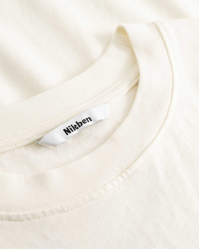 Closeup view of Nikben necklabel on cream colored T-shirt