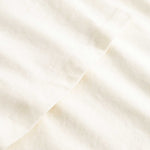 Closeup view of arm stitchings on cream colored T-shirt