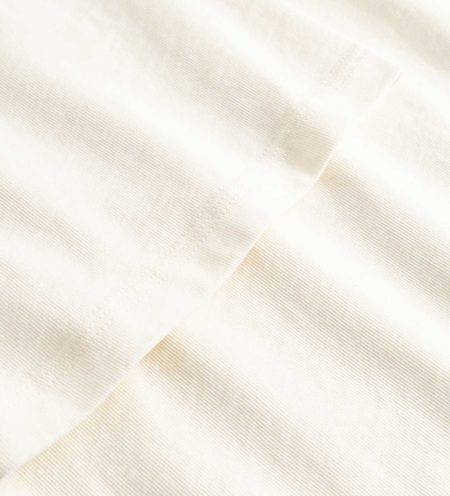 Closeup view of arm stitchings on cream colored T-shirt