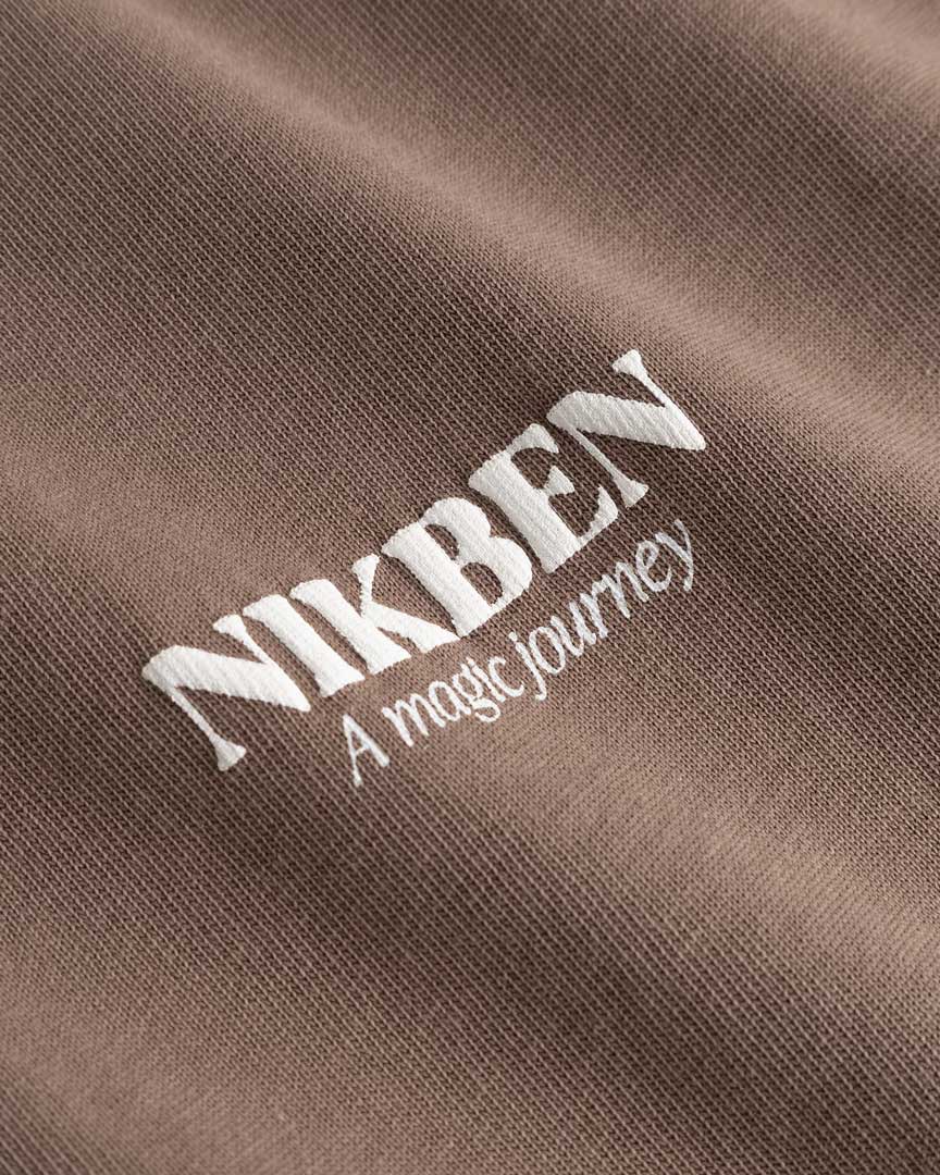 Closeup of white Nikben logo on brown T-shirt
