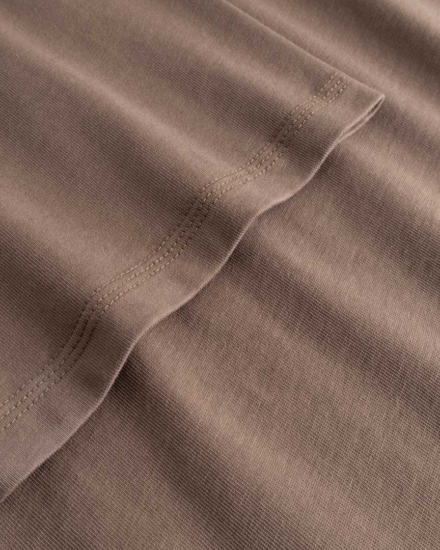 Closeup view of arm stitchings on brown T-shirt
