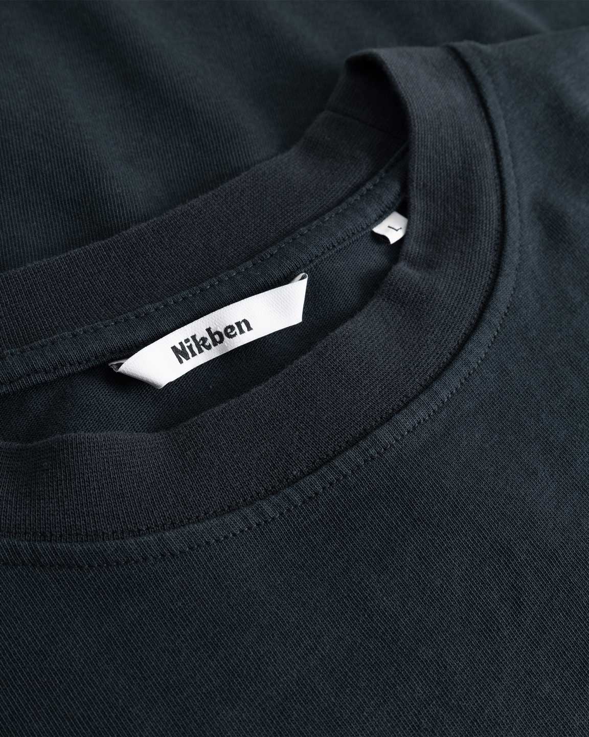 Closeup view of Nikben necklabel on black T-shirt