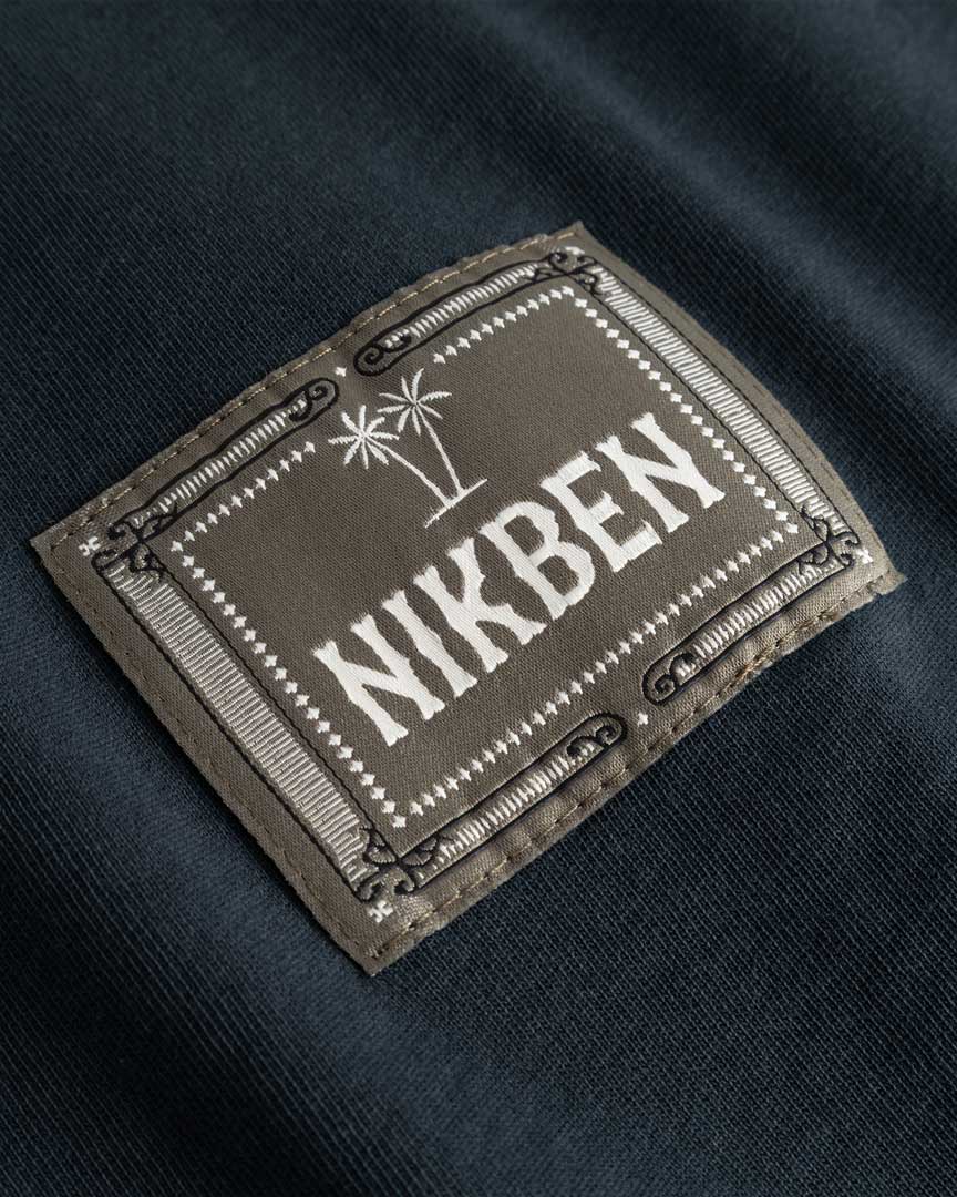 Closeup view of green Nikben patch logo on black T-shirt