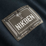 Closeup view of green Nikben patch logo on black T-shirt