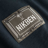 Closeup view of green Nikben patch logo on black T-shirt