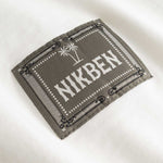 Closeup view of green Nikben patch logo on white T-shirt