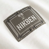 Closeup view of green Nikben patch logo on white T-shirt