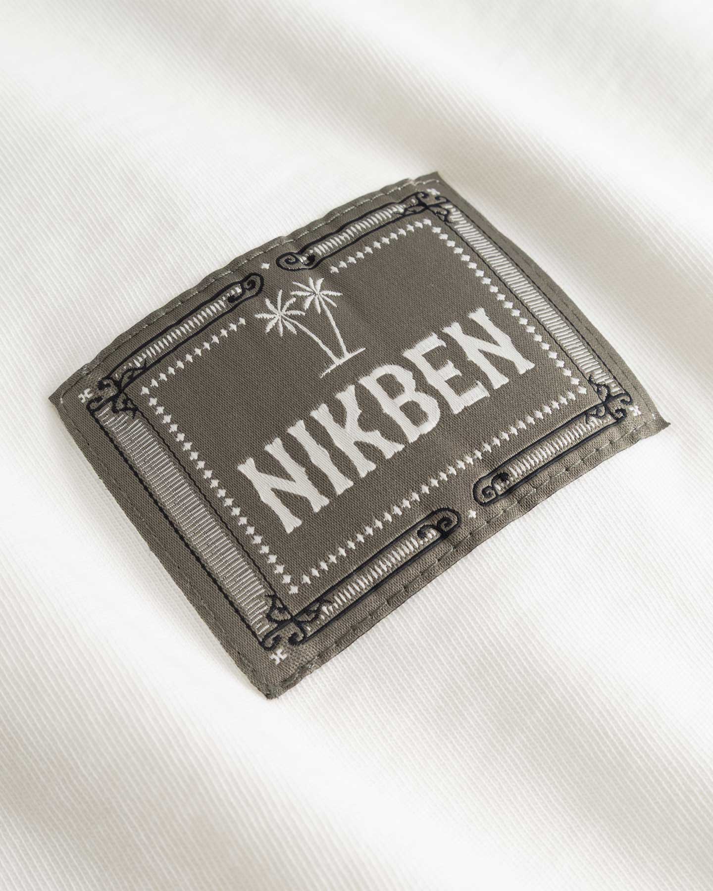 Closeup view of green Nikben patch logo on white T-shirt