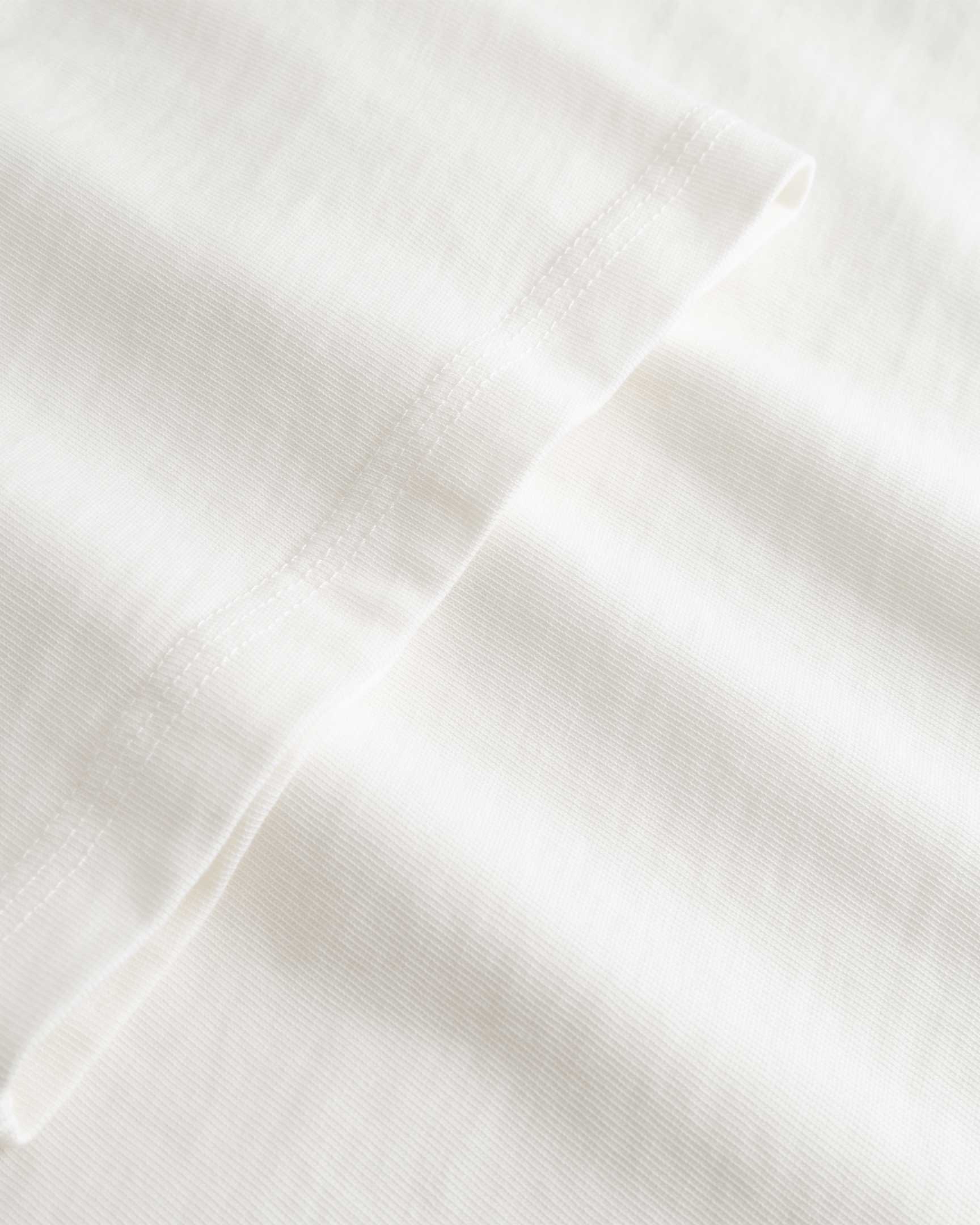 Closeup view of arm stitchings on white T-shirt