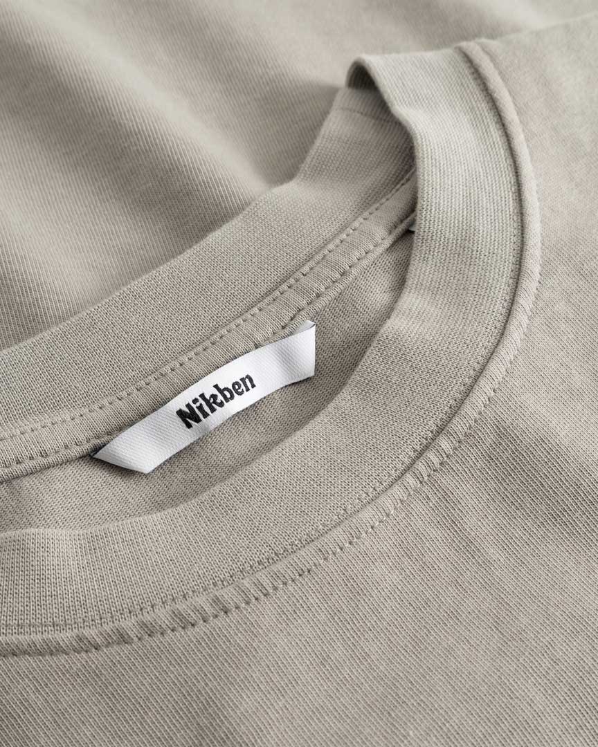 Closeup view of Nikben necklabel on beige T-shirt