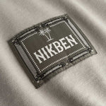 Closeup view of green Nikben patch logo on beige T-shirt